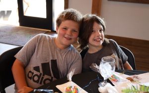 two kids sitting at a table smiling